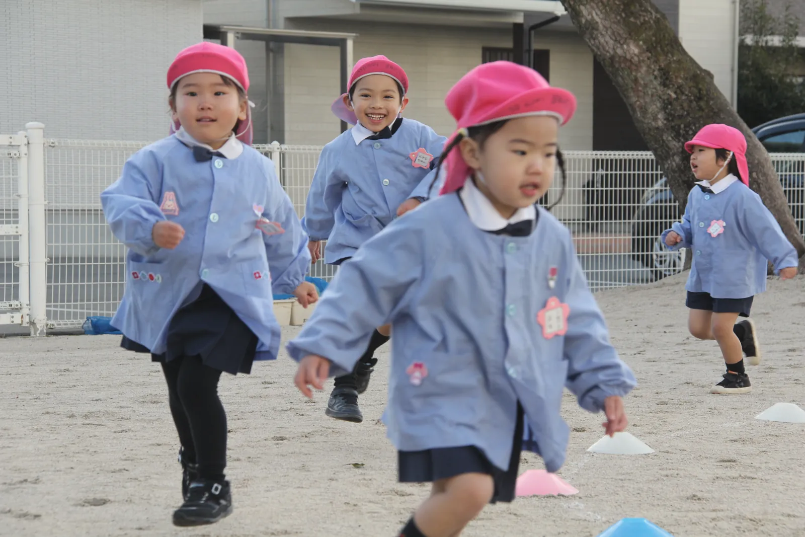 赤い帽子をかぶって園庭を走る子どもたち
